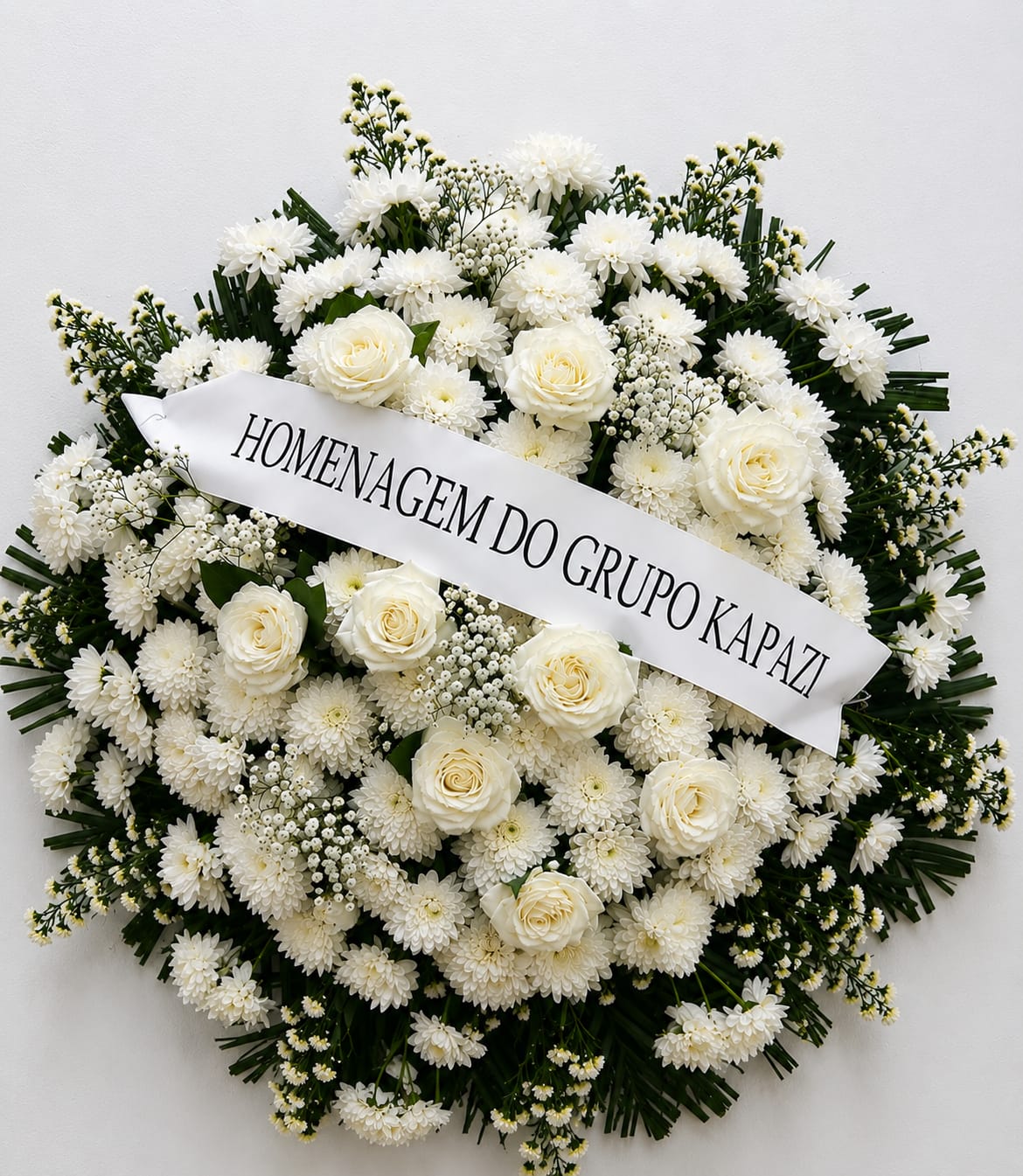Coroa de flores brancas com faixa de homenagem
